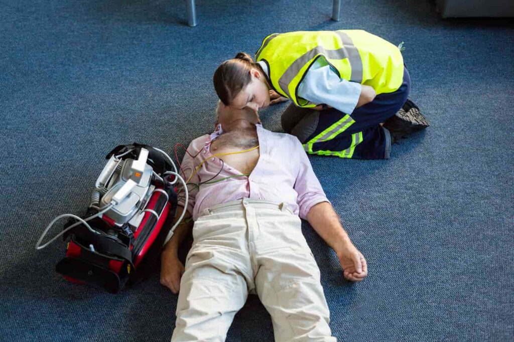 Paramedic performing CPR during emergency first aid training at work